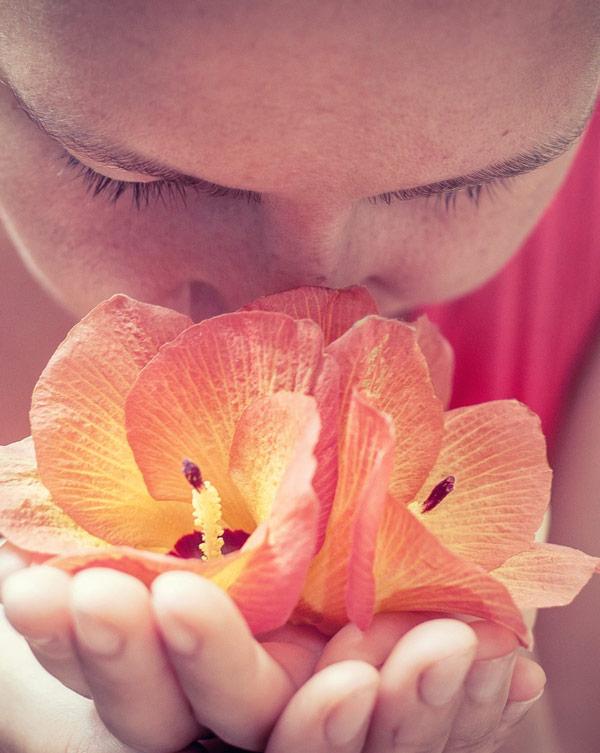 Soothe More than Just Your Skin with KULCBD image of woman deeply smelling orange flower